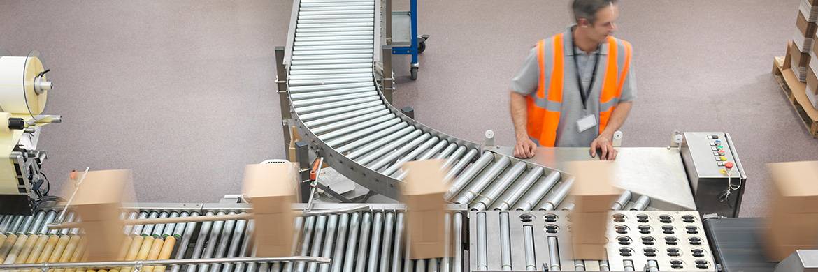 Worker standing next to a conveyor belt moving packages